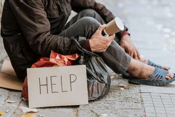 Homeless man holds a cup for donation